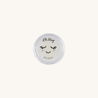 Round container of 'Oh Flossy' primer with a smiley face design on a white background