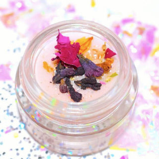 Small container of unicorn lip balm by Plant Makeup - pink lip gloss with colorful dried flowers on a white background