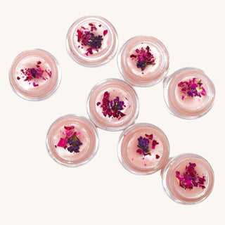 Unicorn lip balm by Plant Makeup - pink lip gloss with colorful dried flowers on a white background