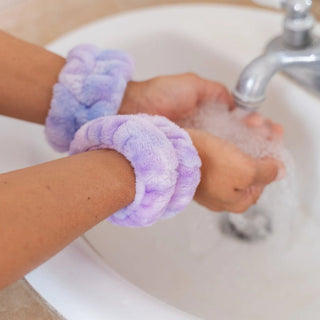 Girl washing hands with purple tie-dye  plush wristbands on wrists in a sink